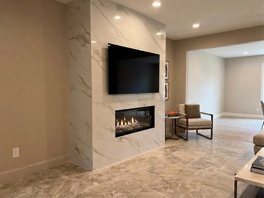 Finished floor-to-ceiling marble-look tile fireplace wall with a linear fireplace and a wall-mounted TV above