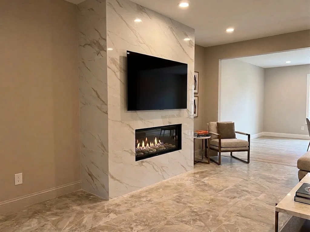 Finished floor-to-ceiling marble-look tile fireplace wall with a linear fireplace and a wall-mounted TV above