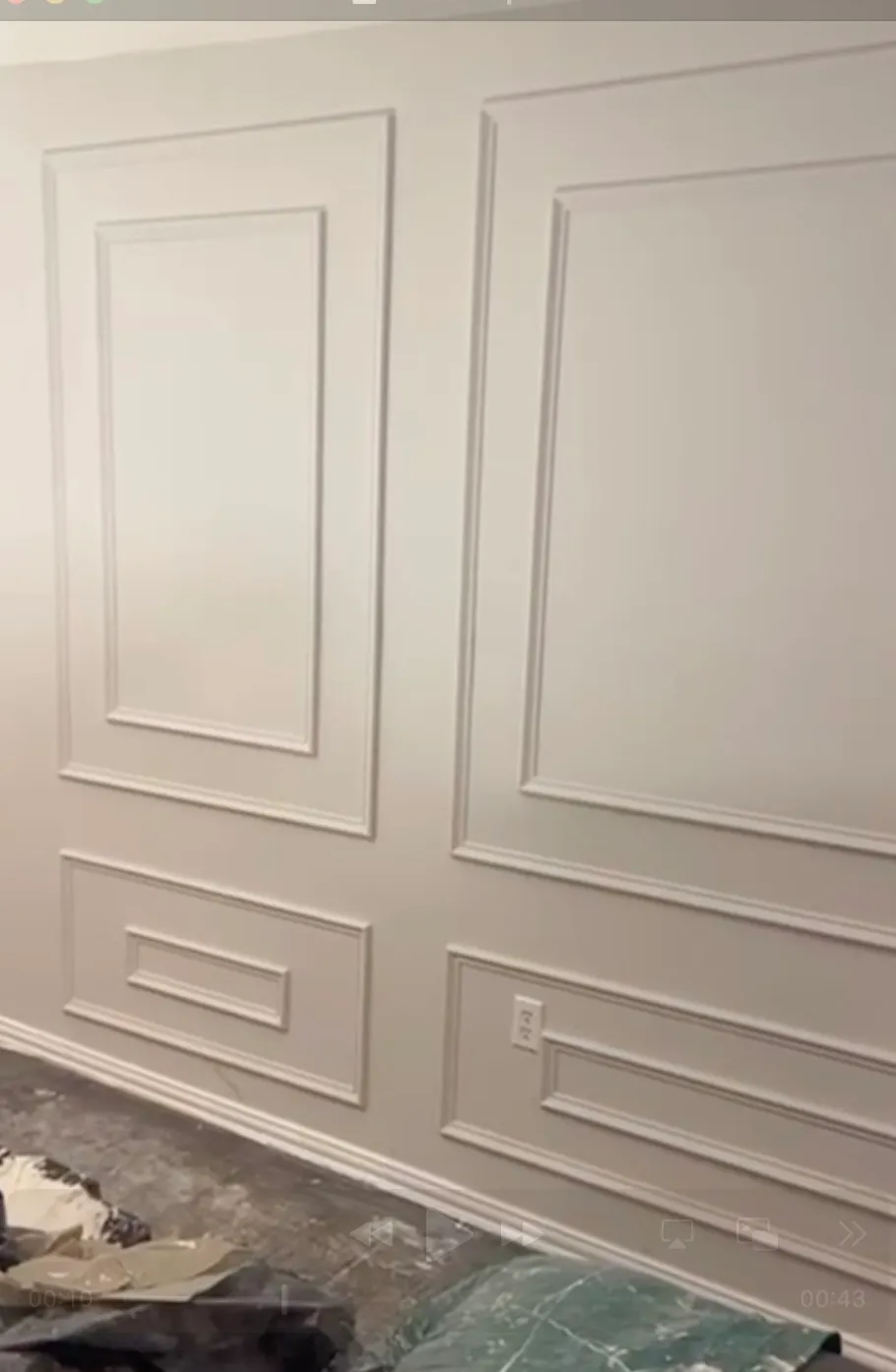 Finished wall of picture-frame molding panels, painted the same soft gray as the wall