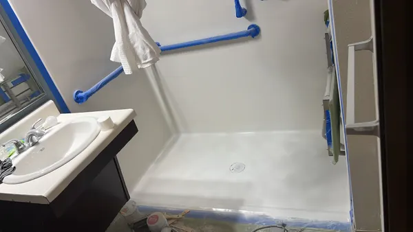 Rental bathroom during make-ready, with blue tape on the grab bars, the mirror edge and the shower pan edges