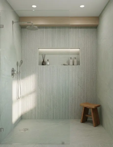 Walk-in shower with a frameless glass panel, textured vertical tile, a lit recessed niche and a wooden stool
