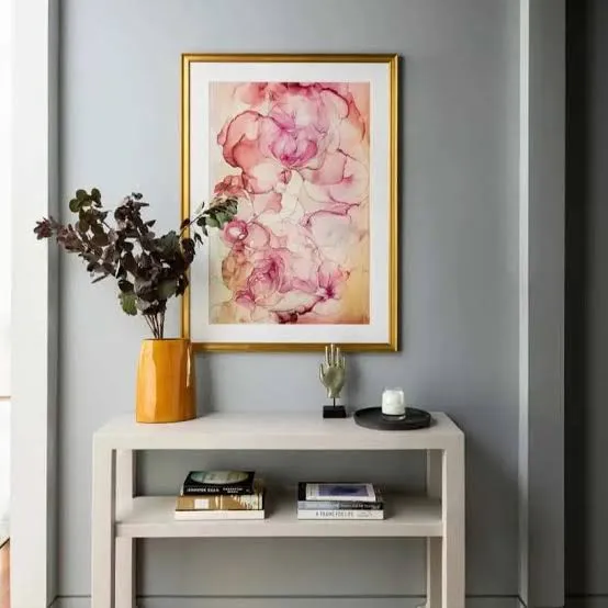 Blue-gray painted wall with a gold-framed floral print above a white console table